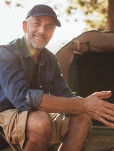 A mature man sitting outside, smiling without TMJ complications.