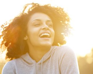 A young woman smiling in the sunset, free of dental anxiety thanks to sedation dentistry.