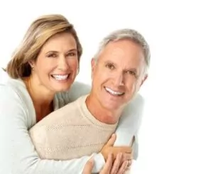 An older couple smiling with each other after dental restoration.