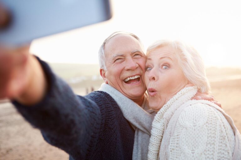 An older couple smiling with each other on the beach after dental restoration.
